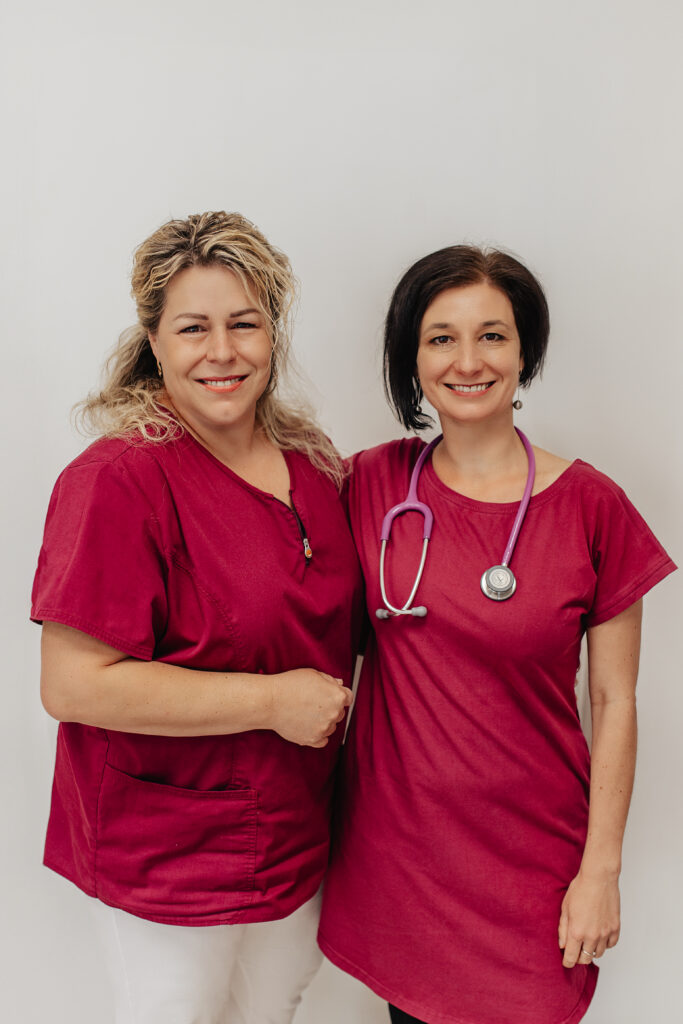 Dvě zdravotnice stojí vedle sebe s překříženými rukama, jeden s fonendoskopem kolem krku, symbolizující týmovou práci a odbornost.